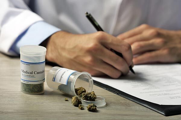 doctor prescribing THCV medical marijuana prescription with a pot of bud on desk